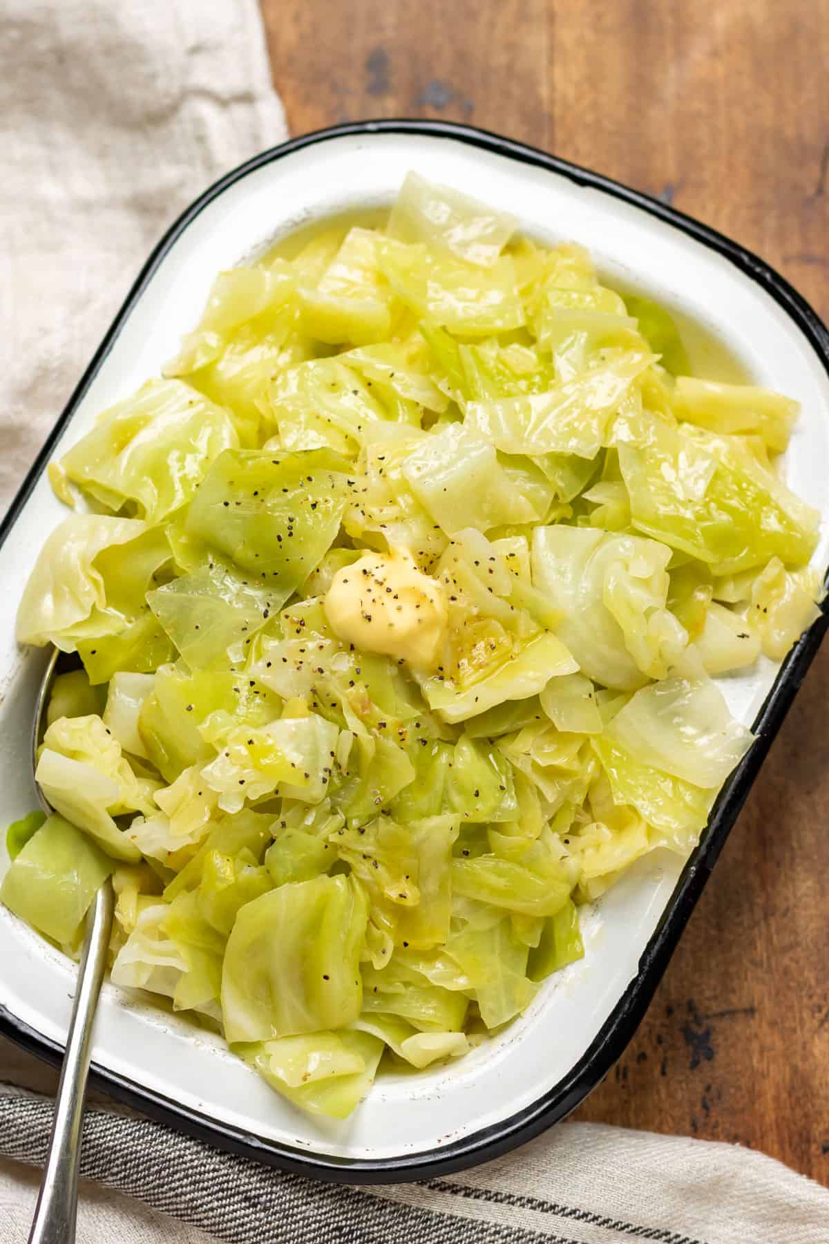 Dish of buttered cabbage on a wooden table.