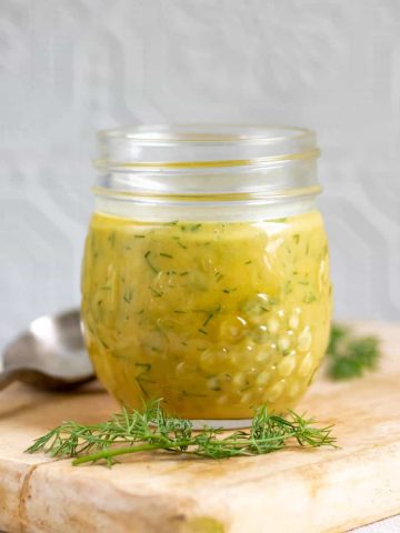 Jar of creamy dill mustard sauce on a table.
