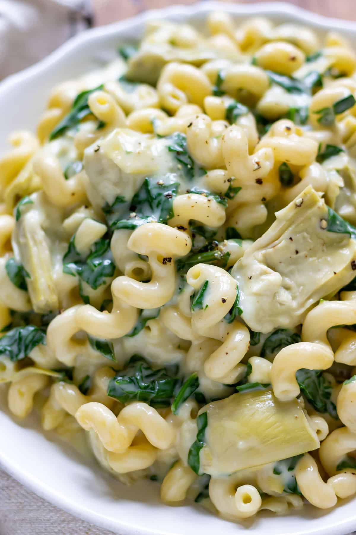 Close up of a plate of pasta with spinach and artichokes.