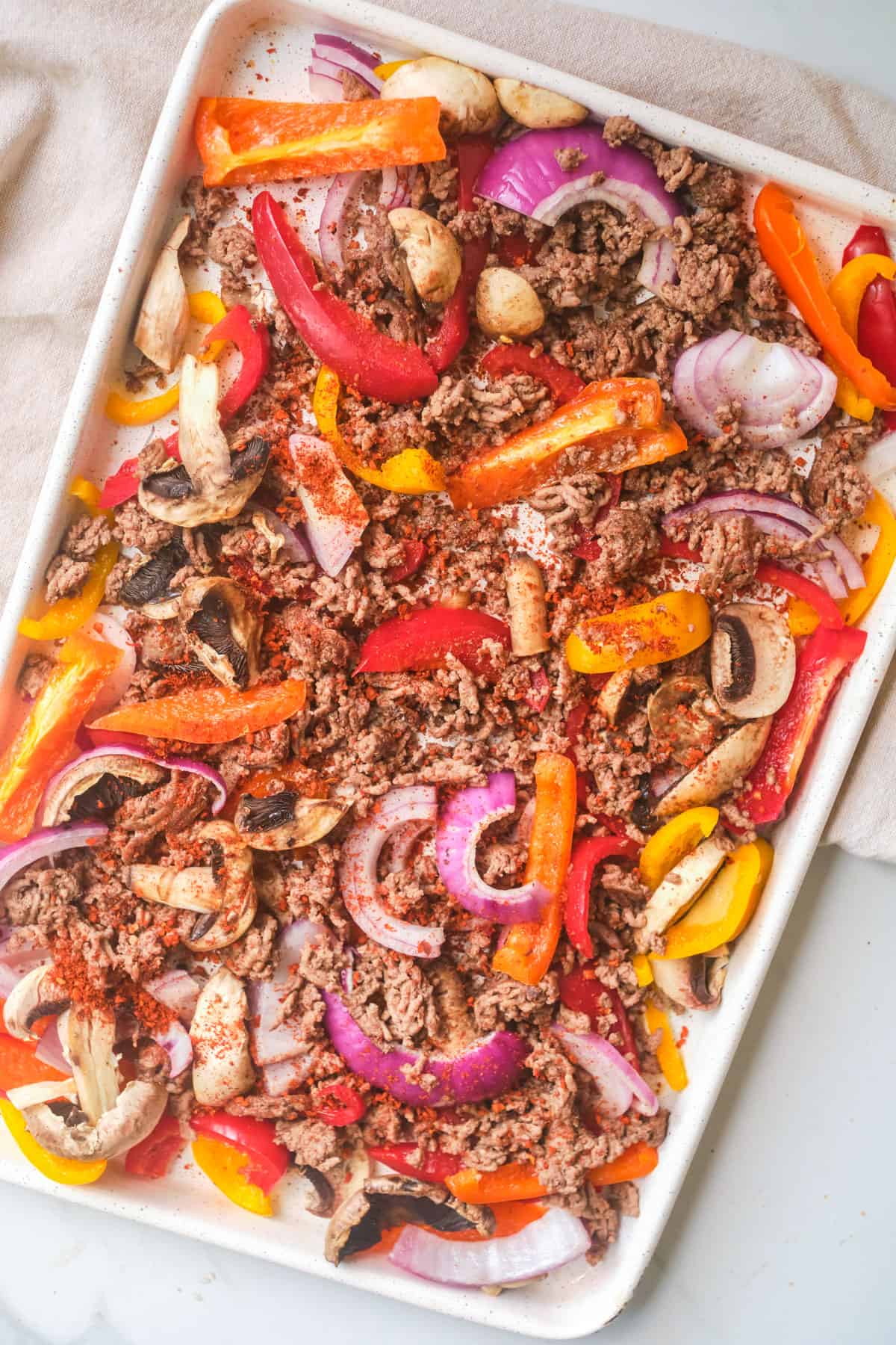 A sheet pan of ground beef and vegetables ready to be roasted.