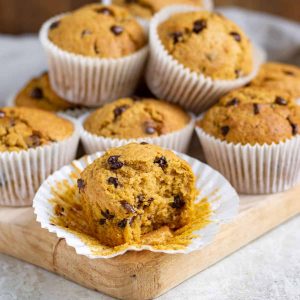 A muffin with a bite out in front of other muffins.
