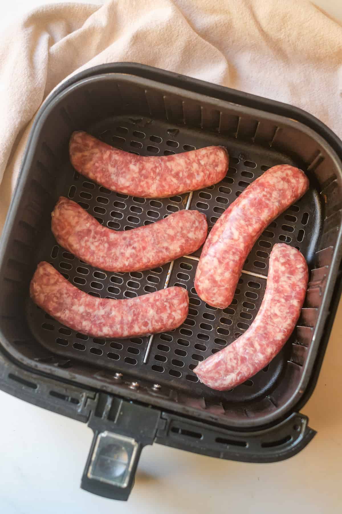 Brats in air fryer ready to be cooked.