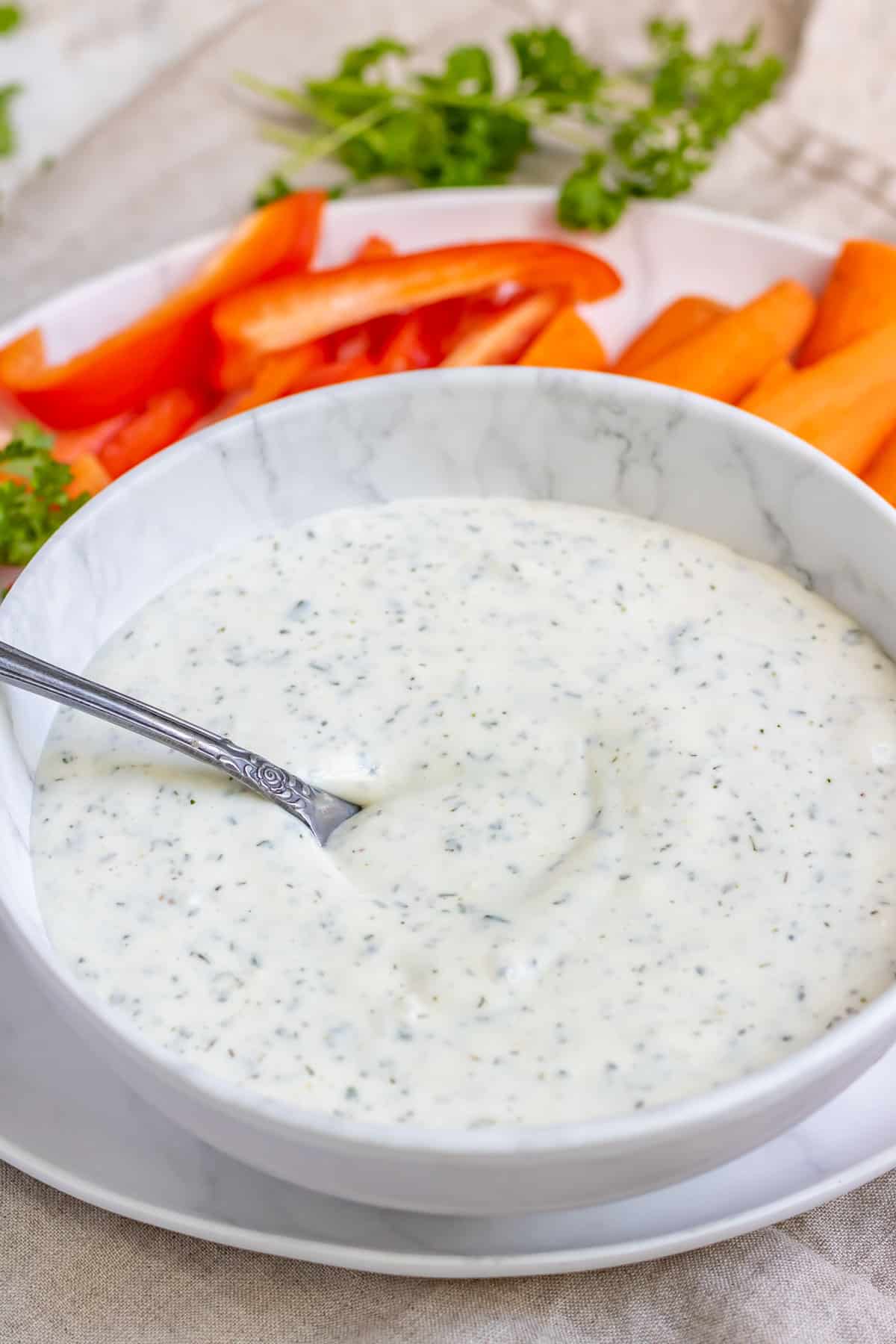 Ranch sauce in a bowl next to raw vegetables.