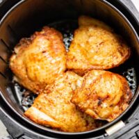 Cooked air fryer chicken thighs in the air fryer basket.
