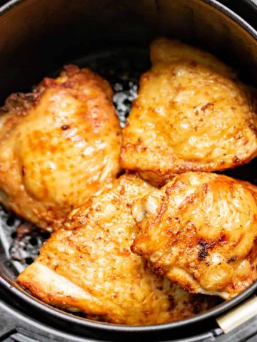 Cooked air fryer chicken thighs in the air fryer basket.