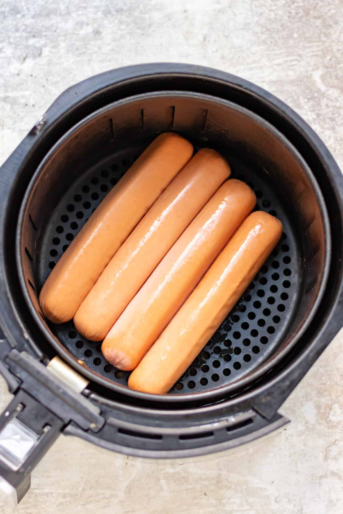 Four hot dogs in an air fryer.