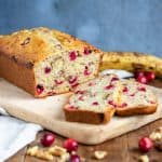 A wooden table with a loaf cake with slices.