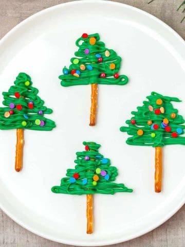 A plate of pretzel sticks covered in green chocolate to look like Xmas trees.