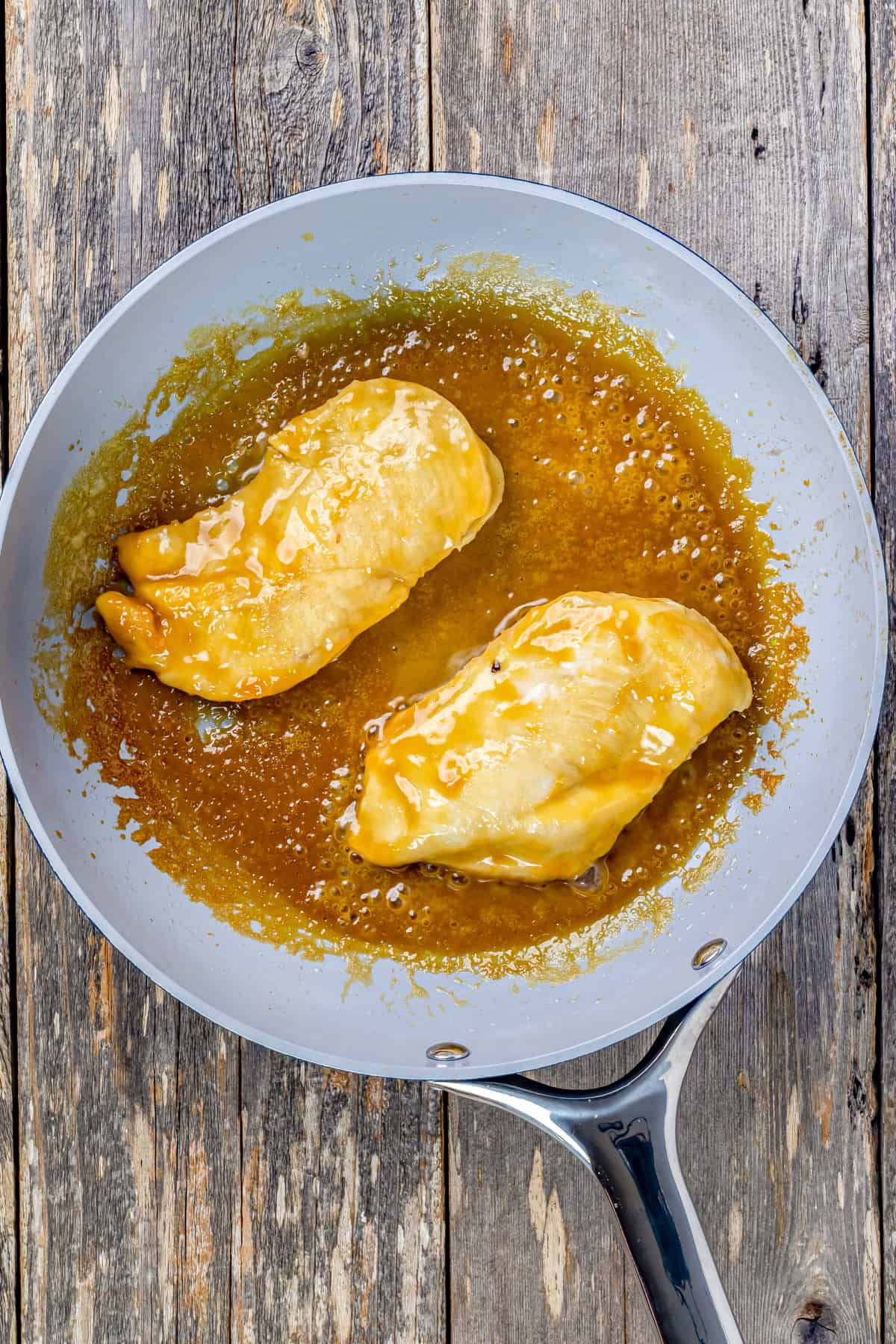 Chicken breasts cooking in a skillet.