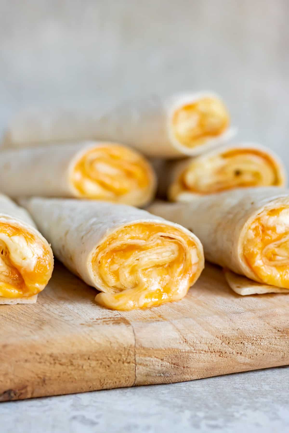 A pile of Taco Bell Cheese Roll Ups on a wooden board.