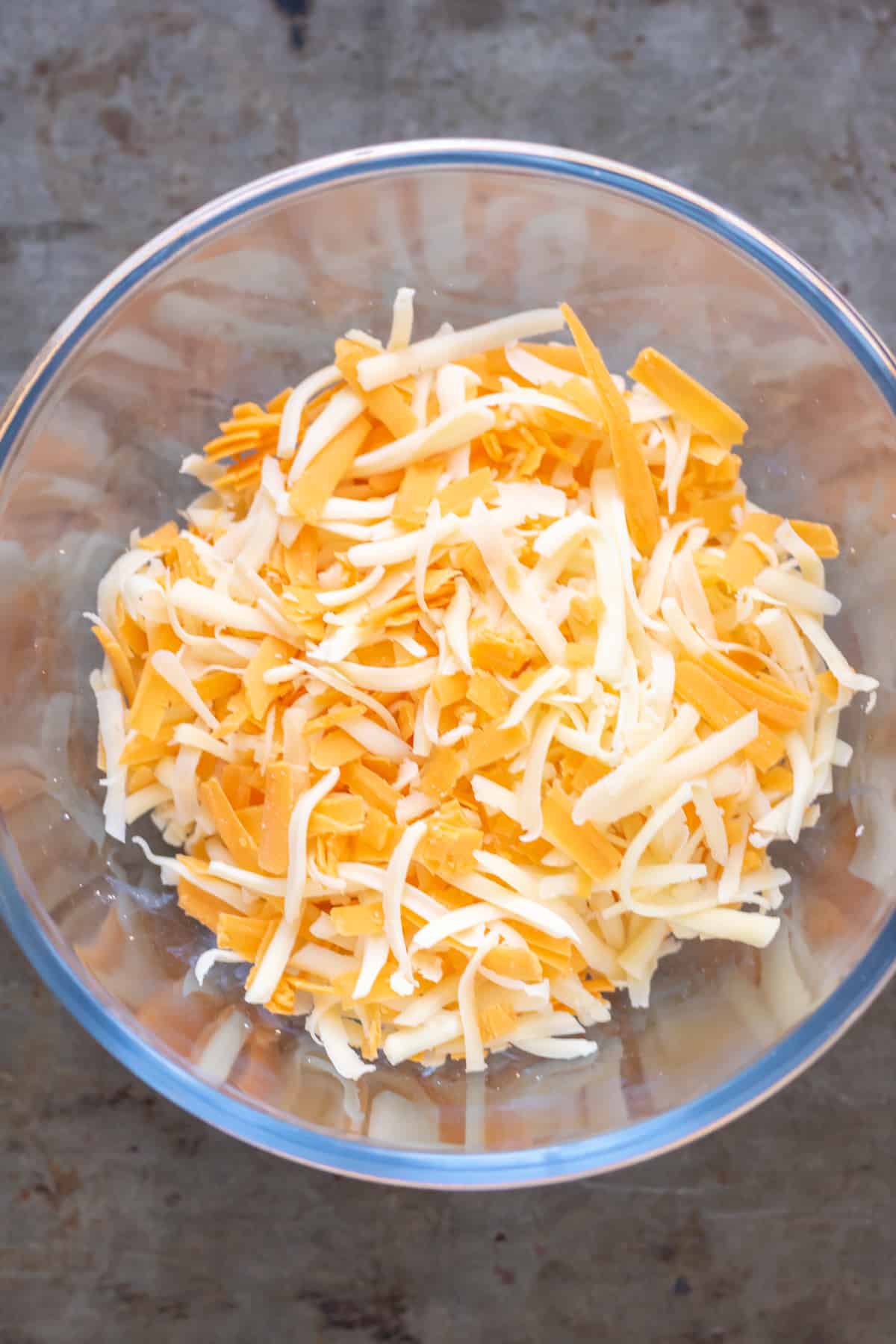 Mixing three types of cheese in a bowl.