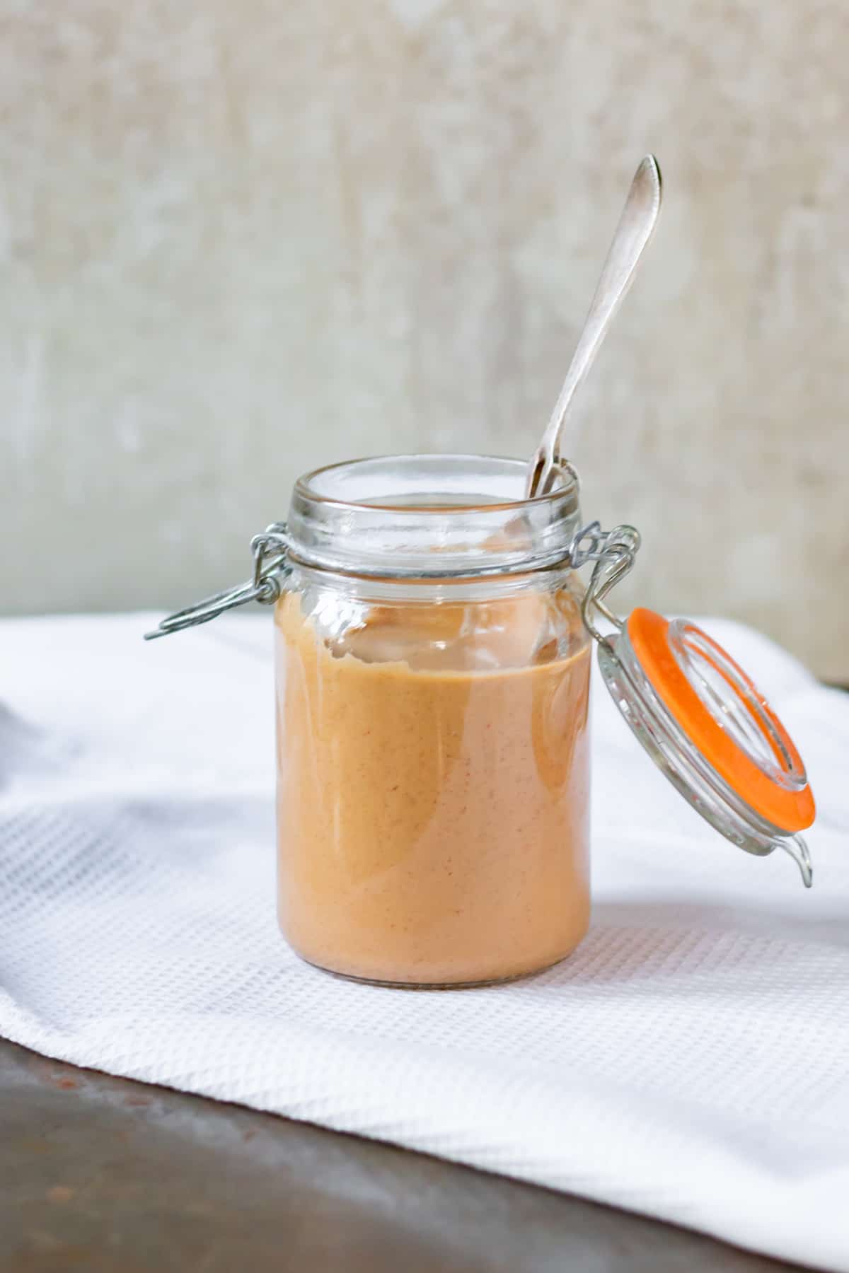 A jar of sauce with a spoon.