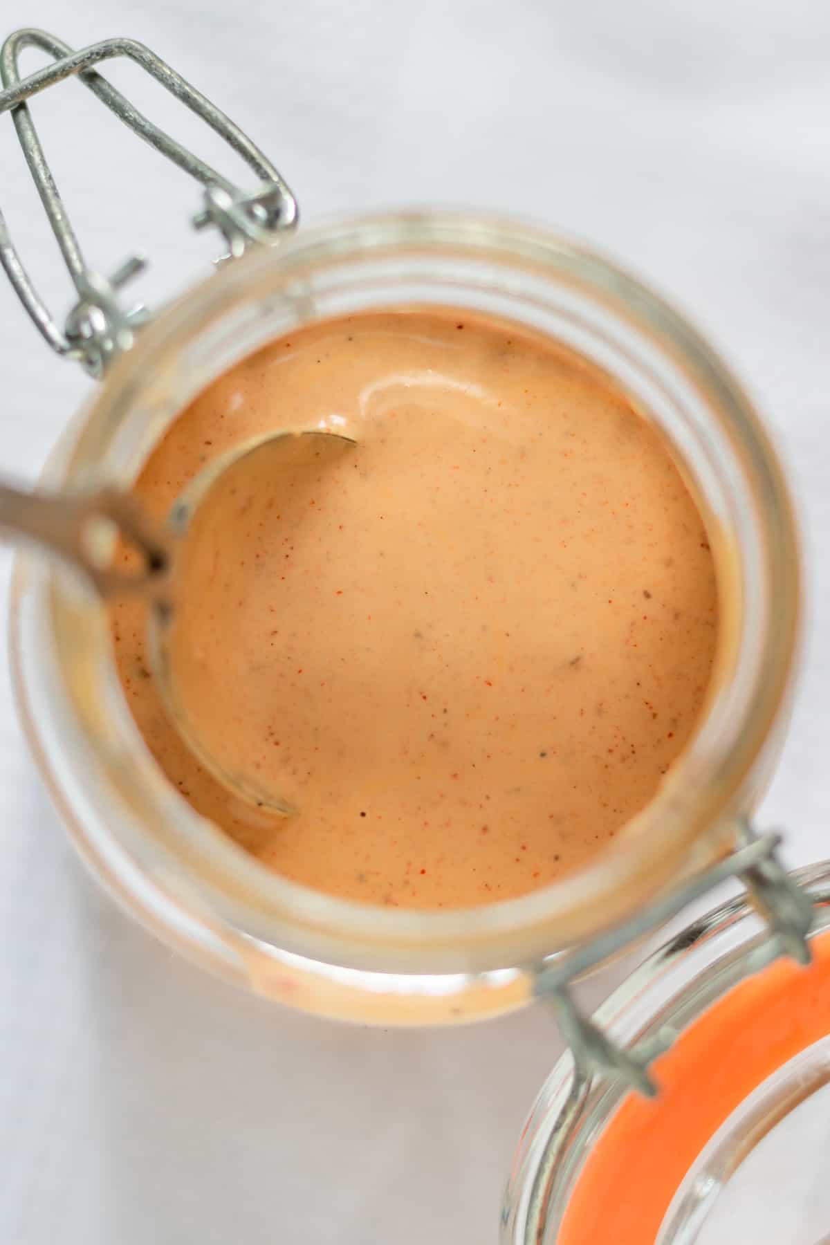 Looking down at a jar of sauce with a spoon in it.