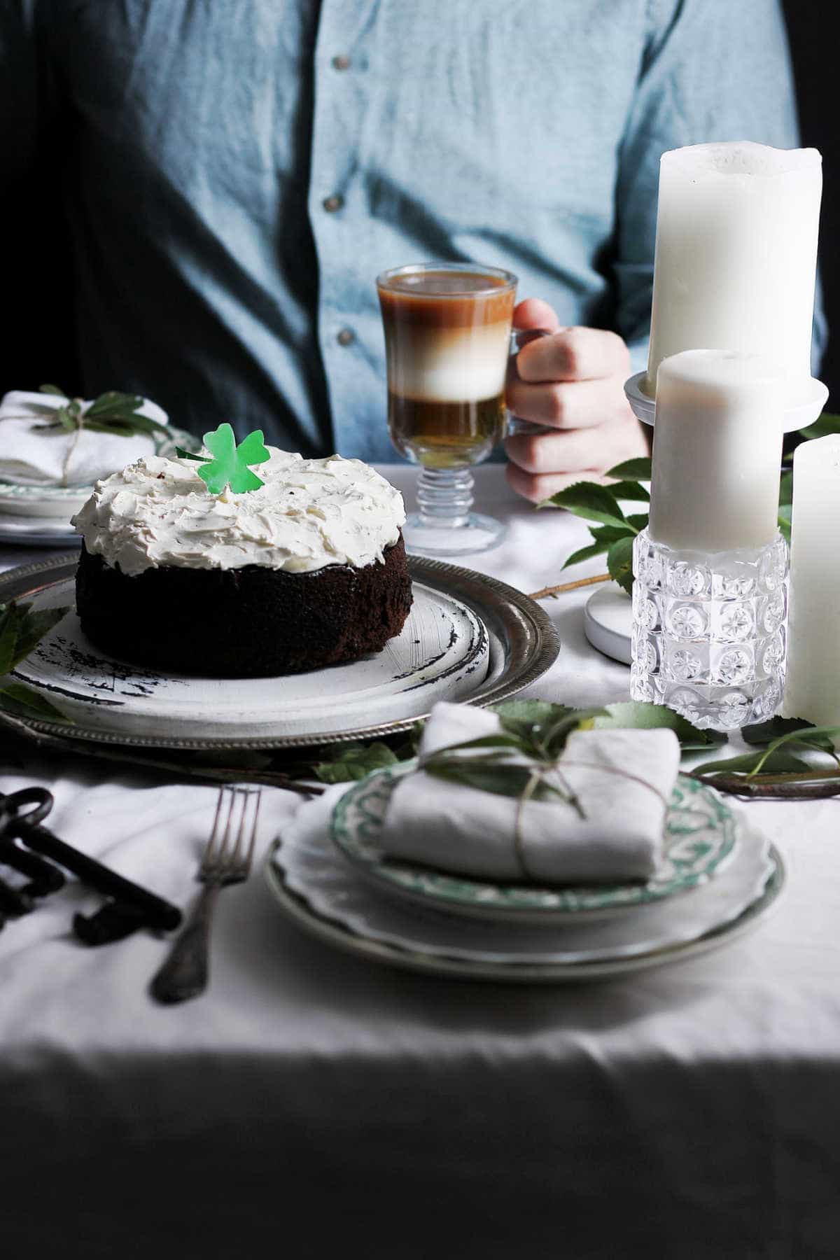 A person at a table with cake and irish coffee.