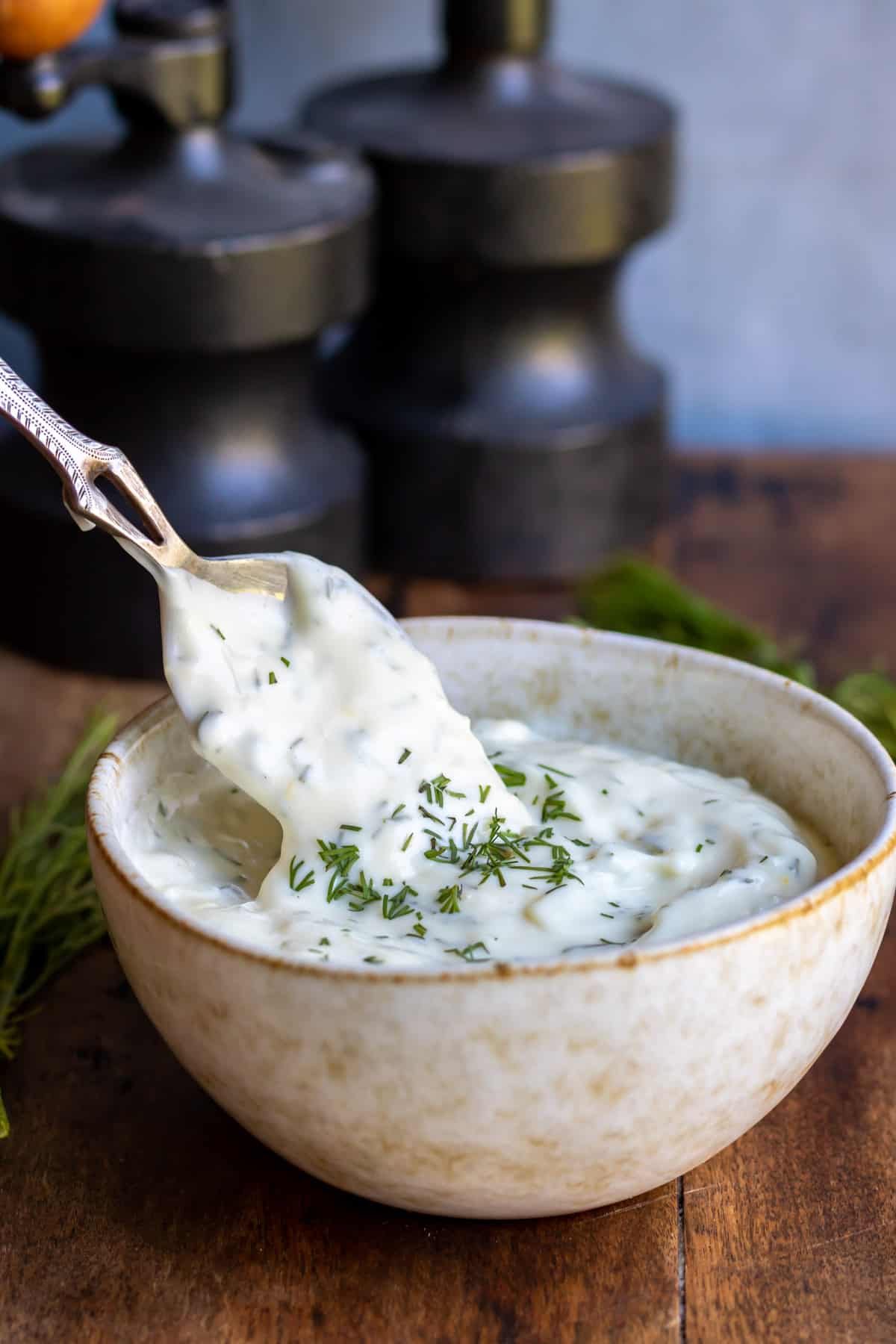 A spoon coming out of a bowl of lemon dill aioli.