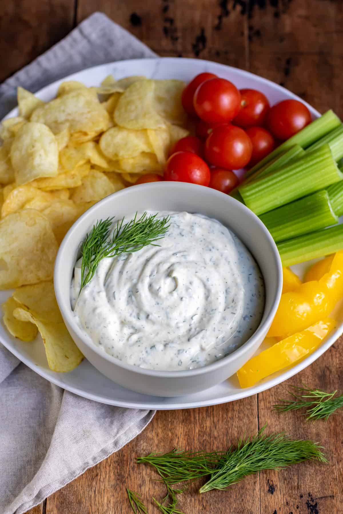 Bowl of dip surrounded by chips and veggies.