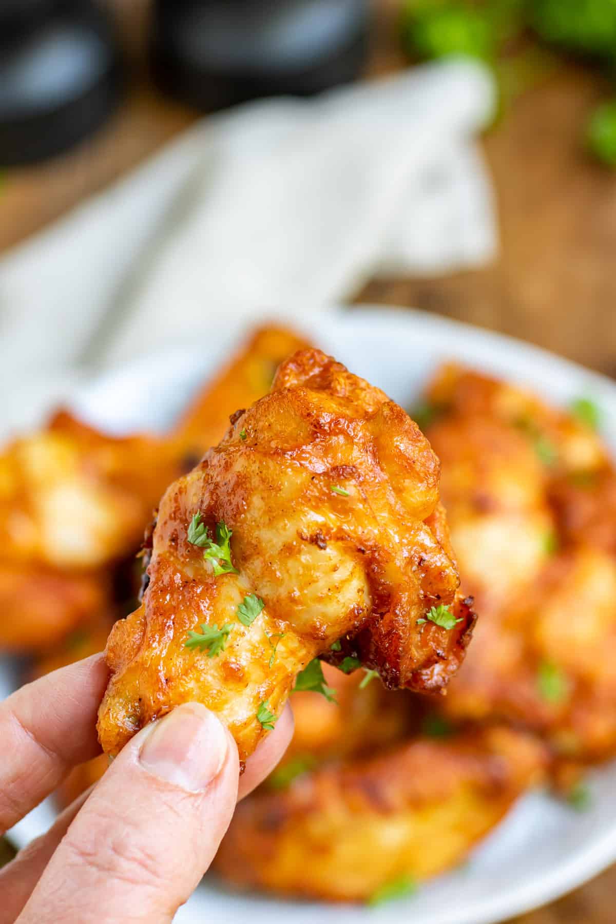 A hand holding up a cajun spiced chicken wing.