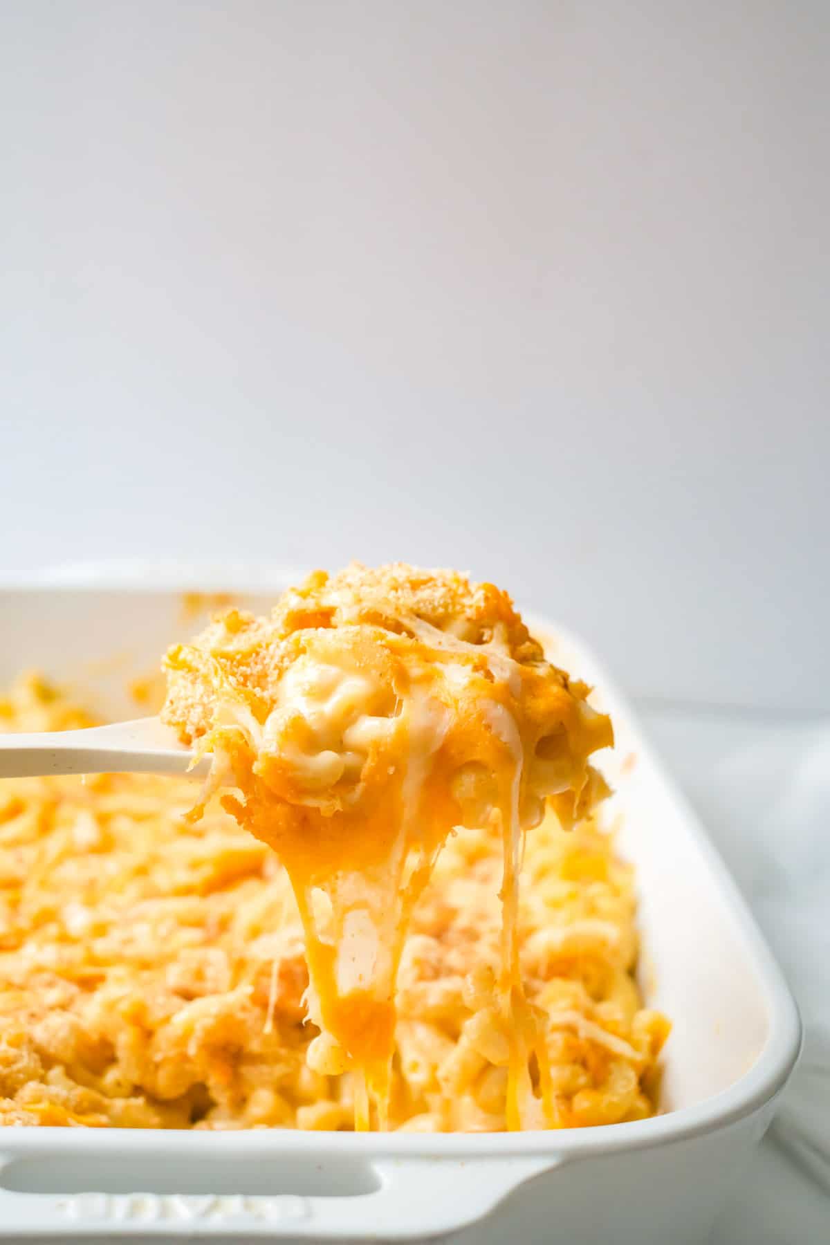 A dish of mac and cheese with a spoonful coming out.