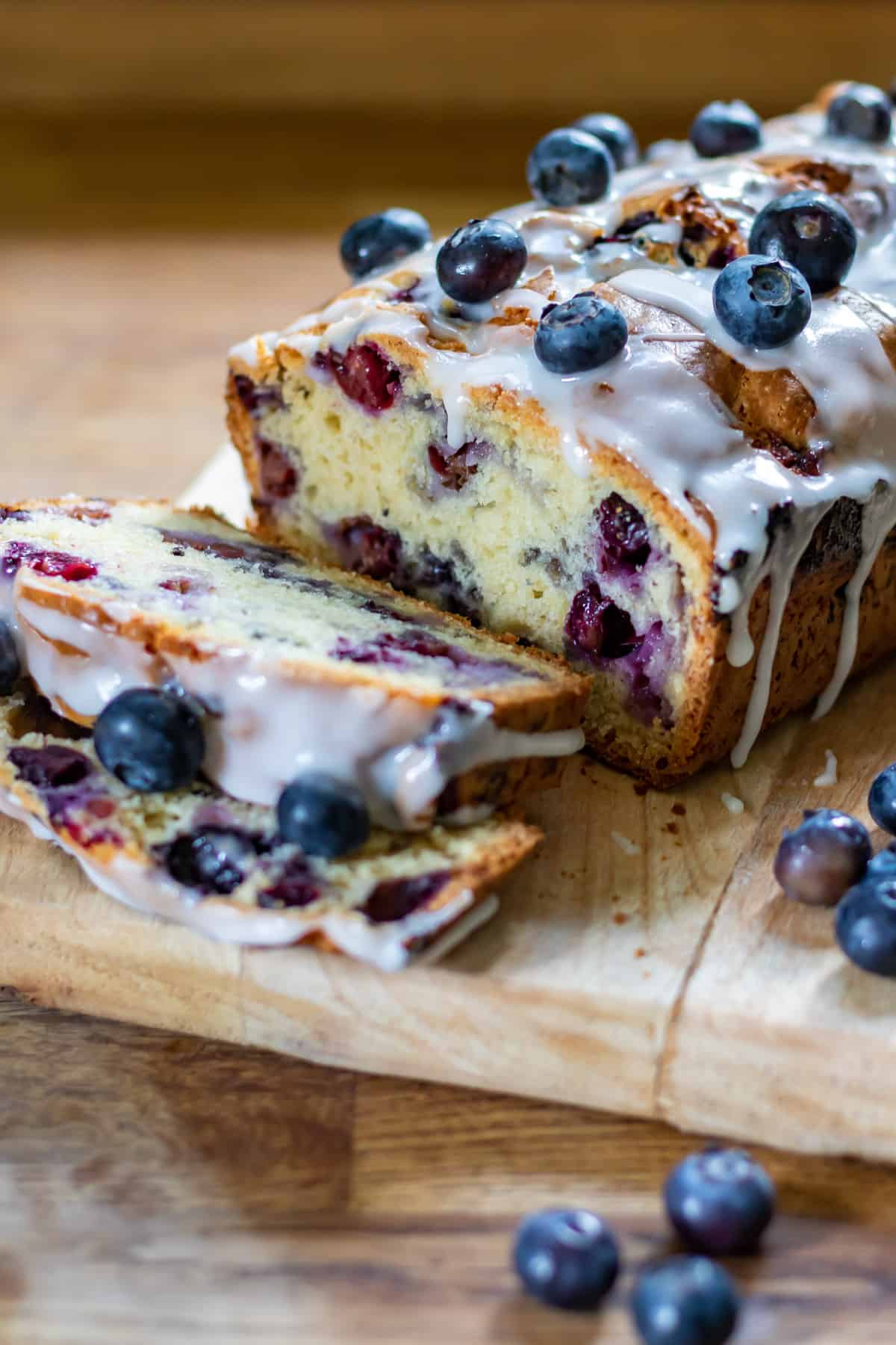 A sliced blueberry bread loaf cake on a wooden board.