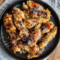 Wooden table with plate of soy garlic chicken wings.