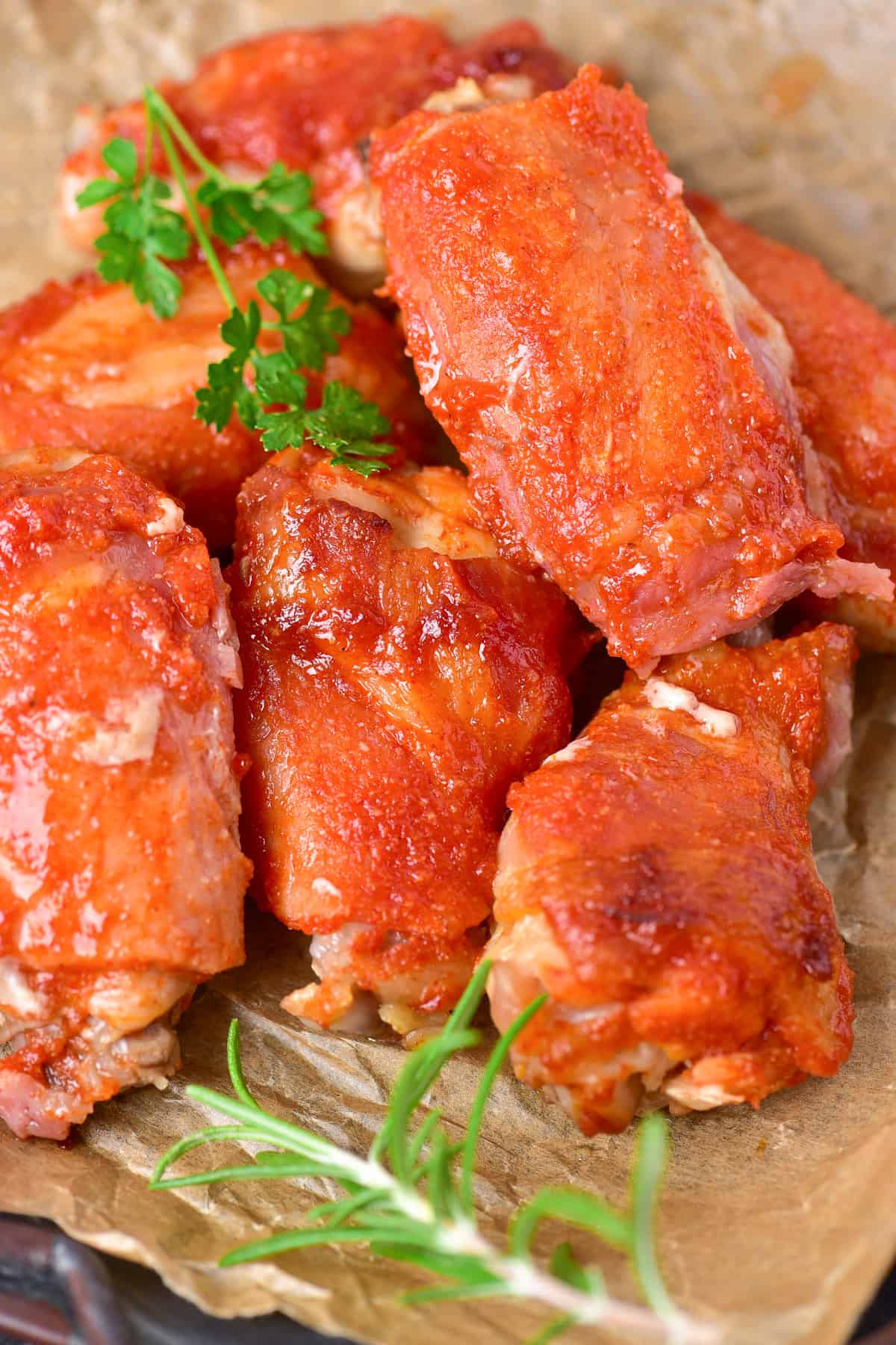 Close up of bacon wrapped wings on a plate with herbs.