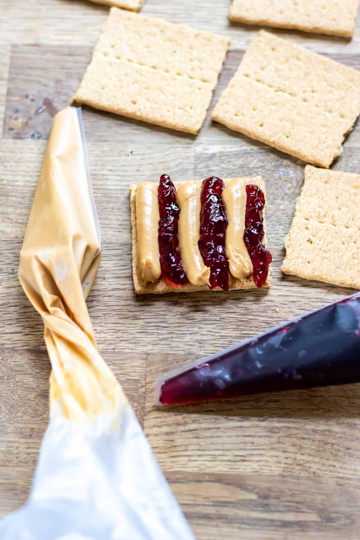 A graham cracker with piped strips of peanut butter and grape jelly.