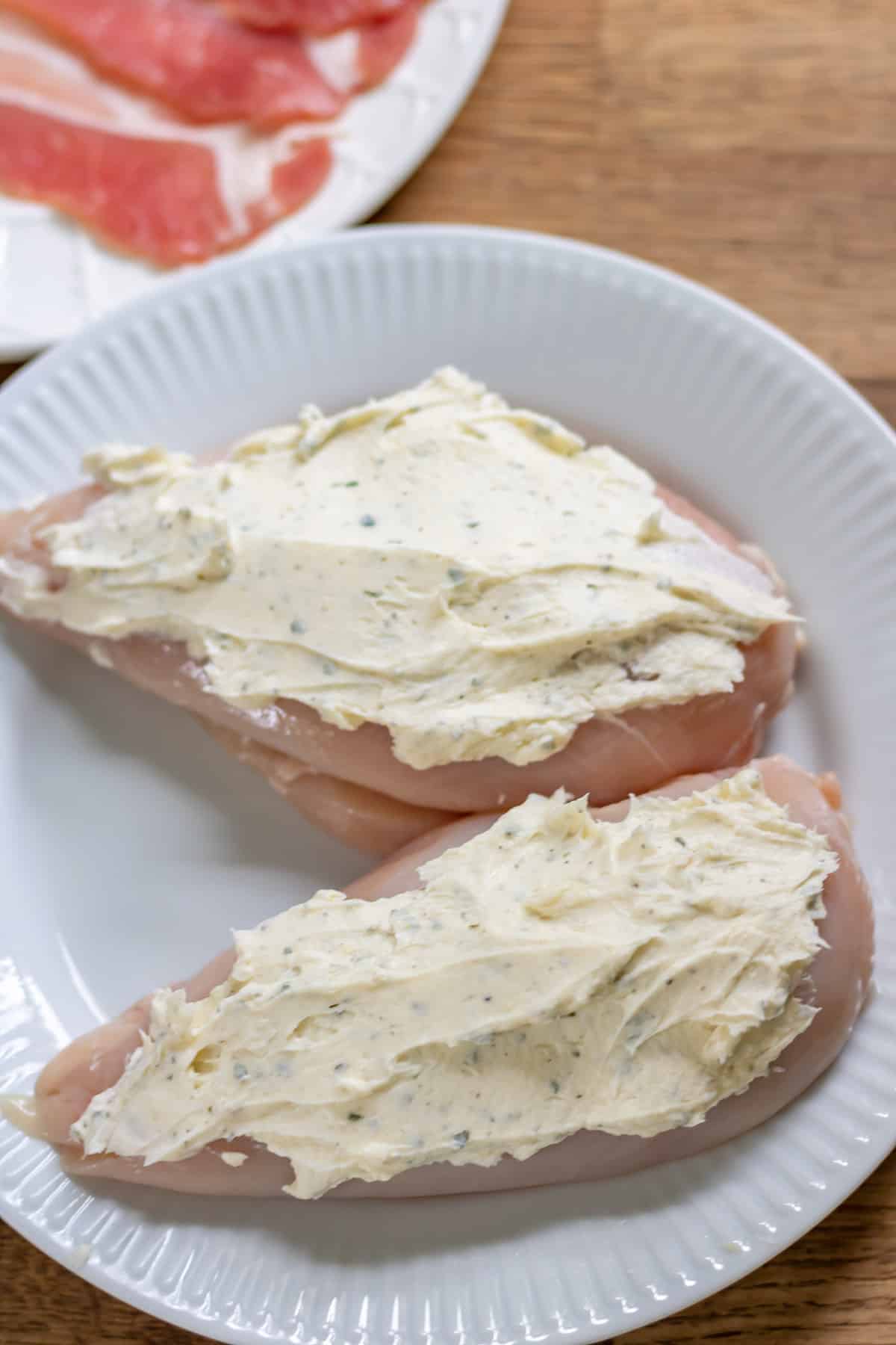 Spreading ranch cream cheese on chicken breasts.
