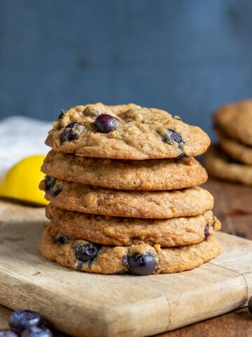 Stack of lemon blueberry cookies on a wooden board.