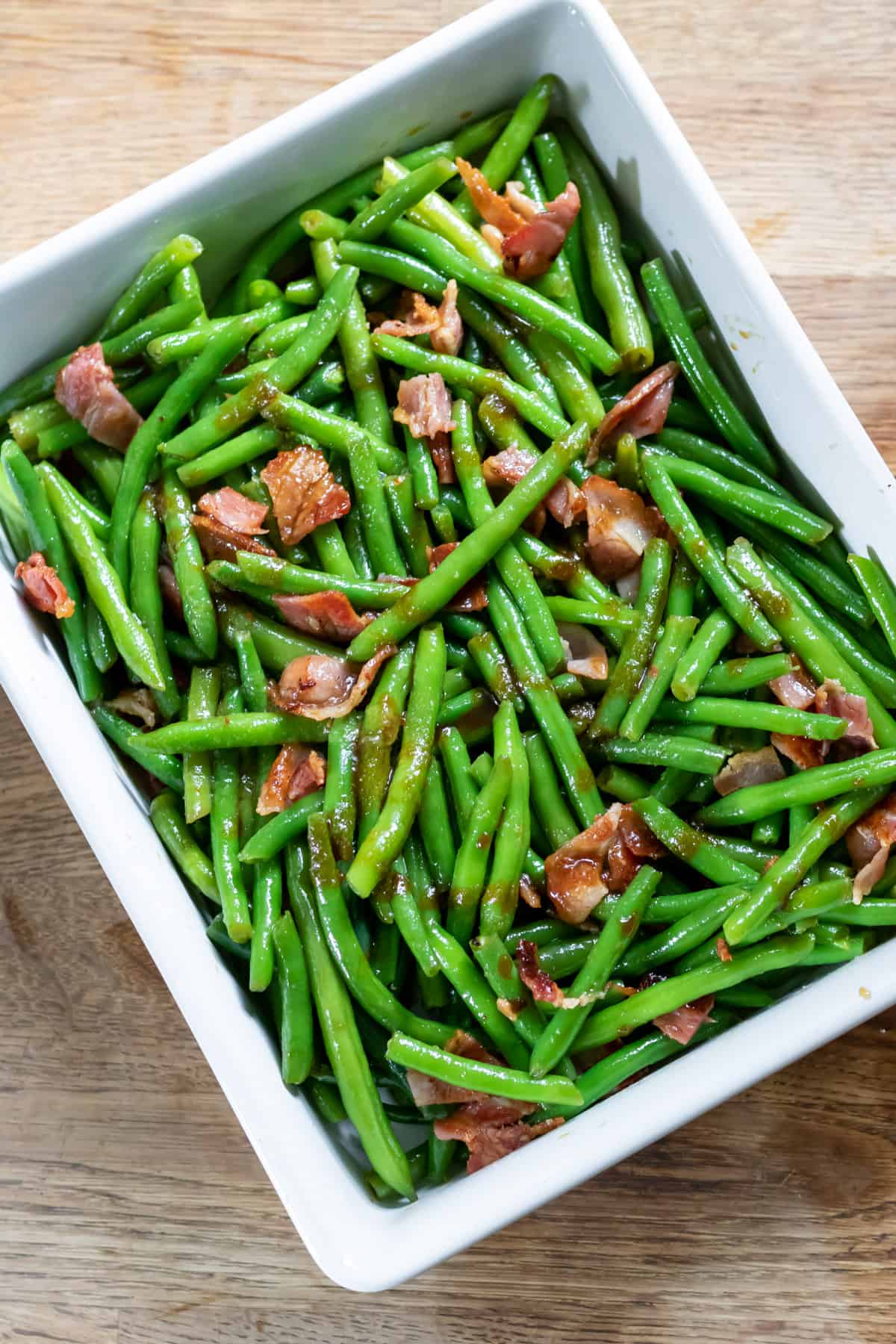 Green beans, bacon and sauce in a dish, ready to bake.