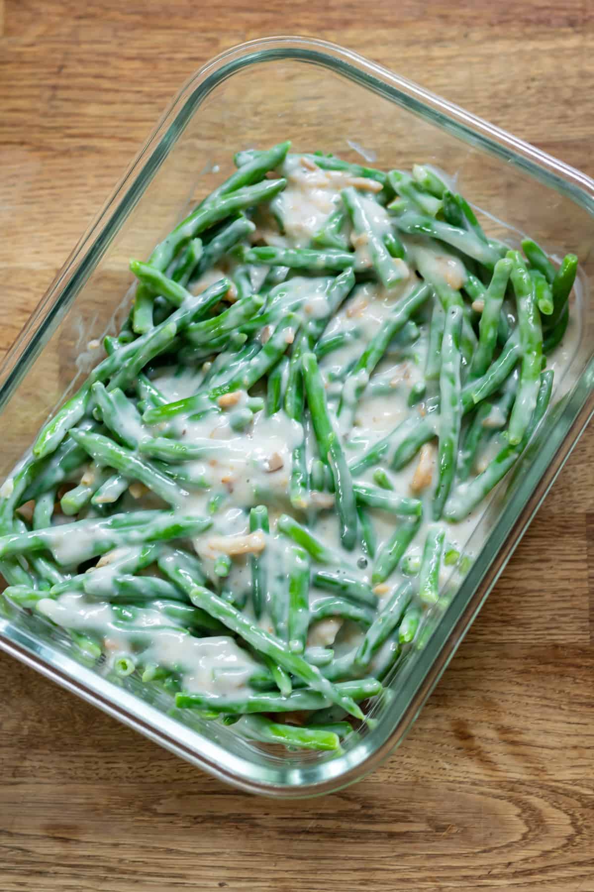 Mixed sauce and green beans in a large glass dish.