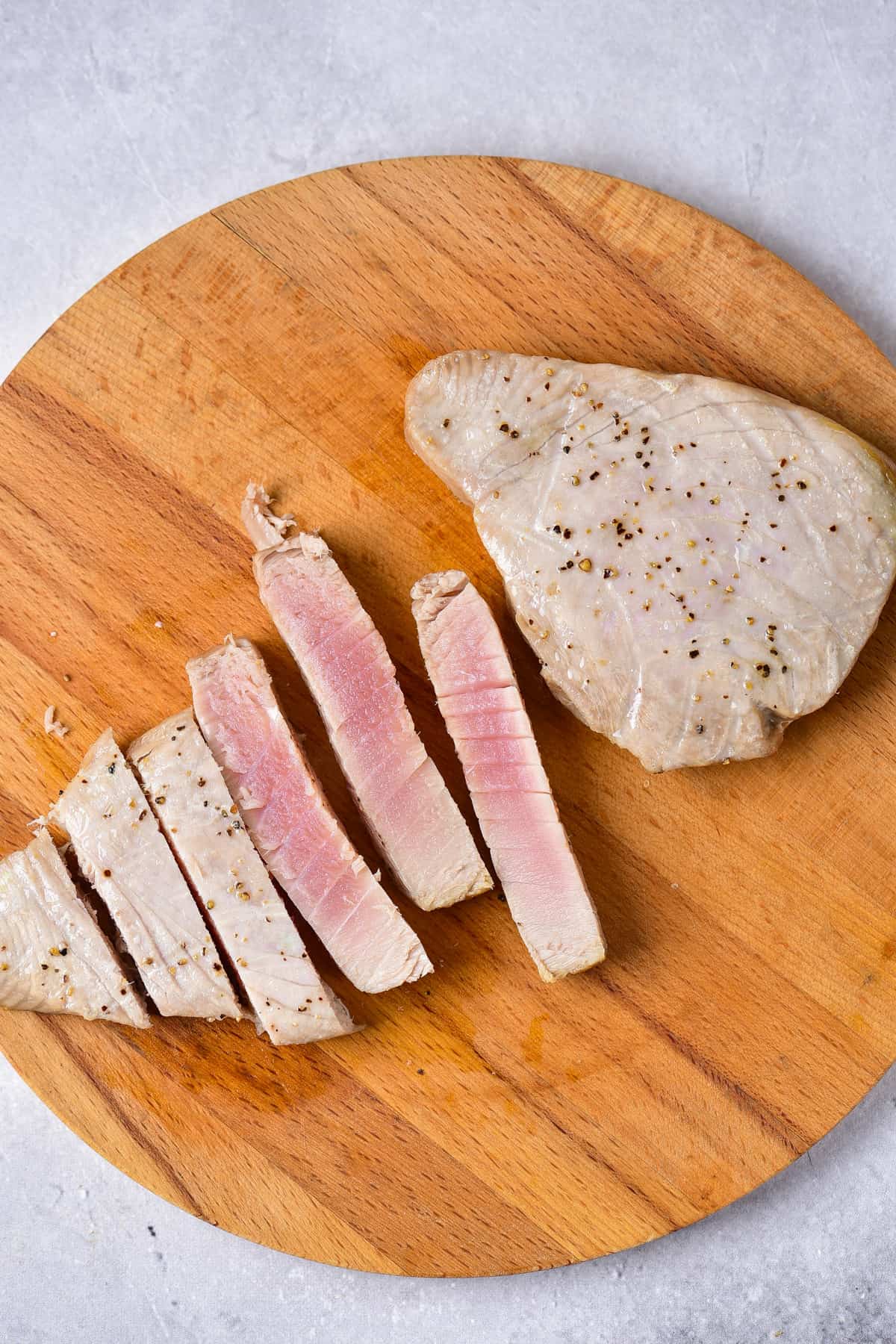 Cutting air fryer tuna steak on a wooden board.