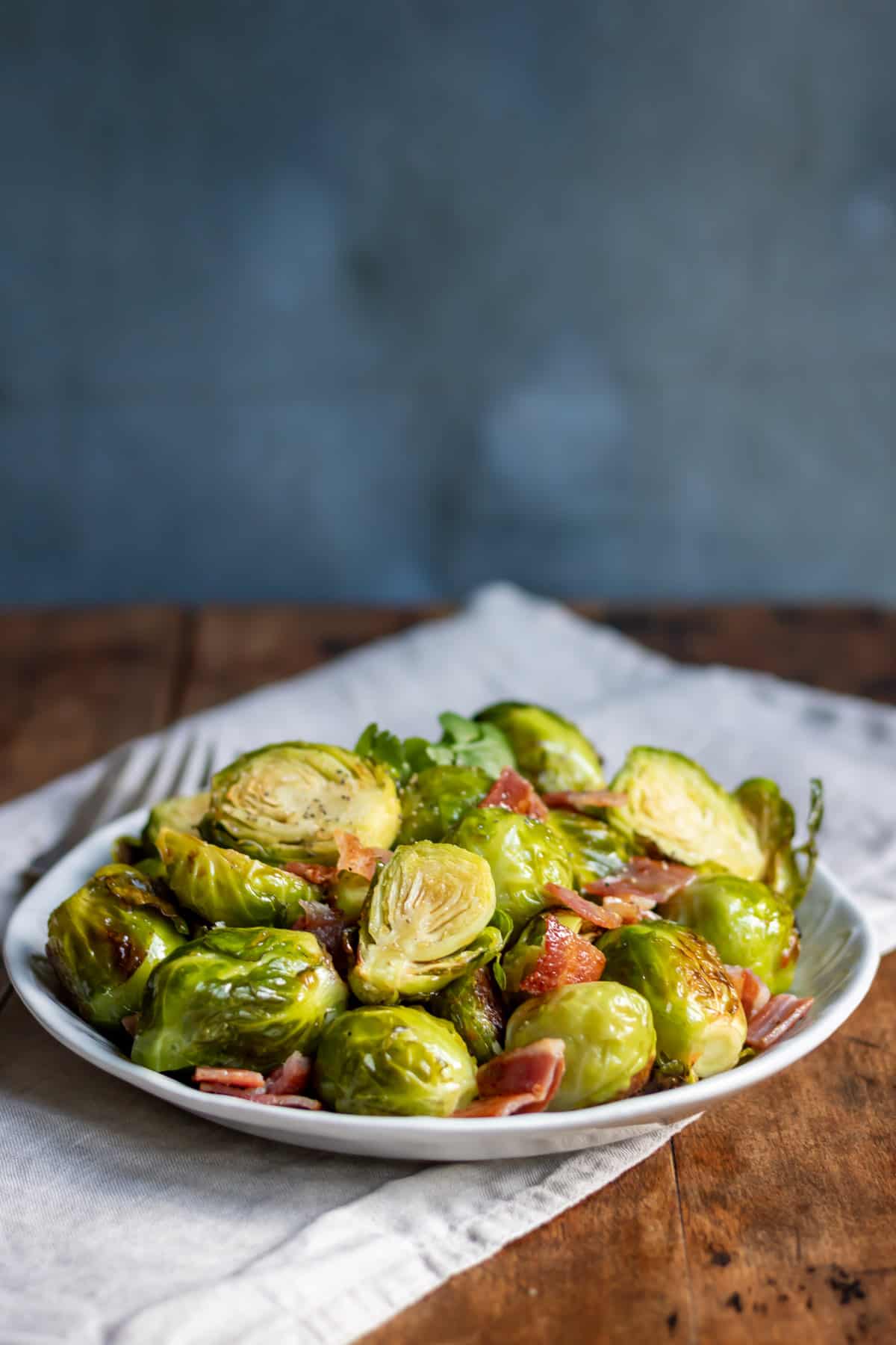 Wooden table with a serving dish of maple bacon brussels sprouts.