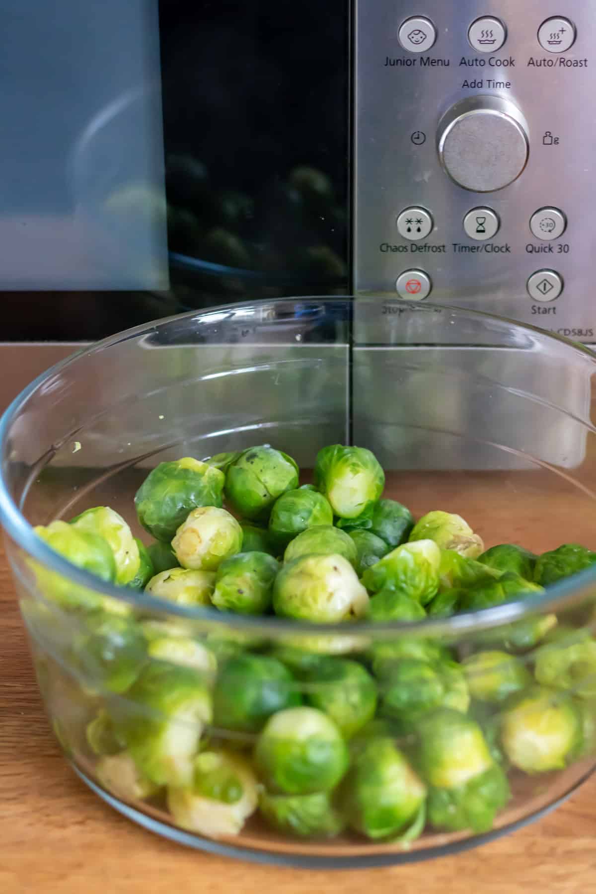 Cooked brussels sprouts in front of a microwave.