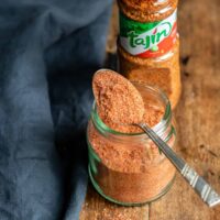 Spoon of tajin resting on a jar, in front of a bottle of tajin.