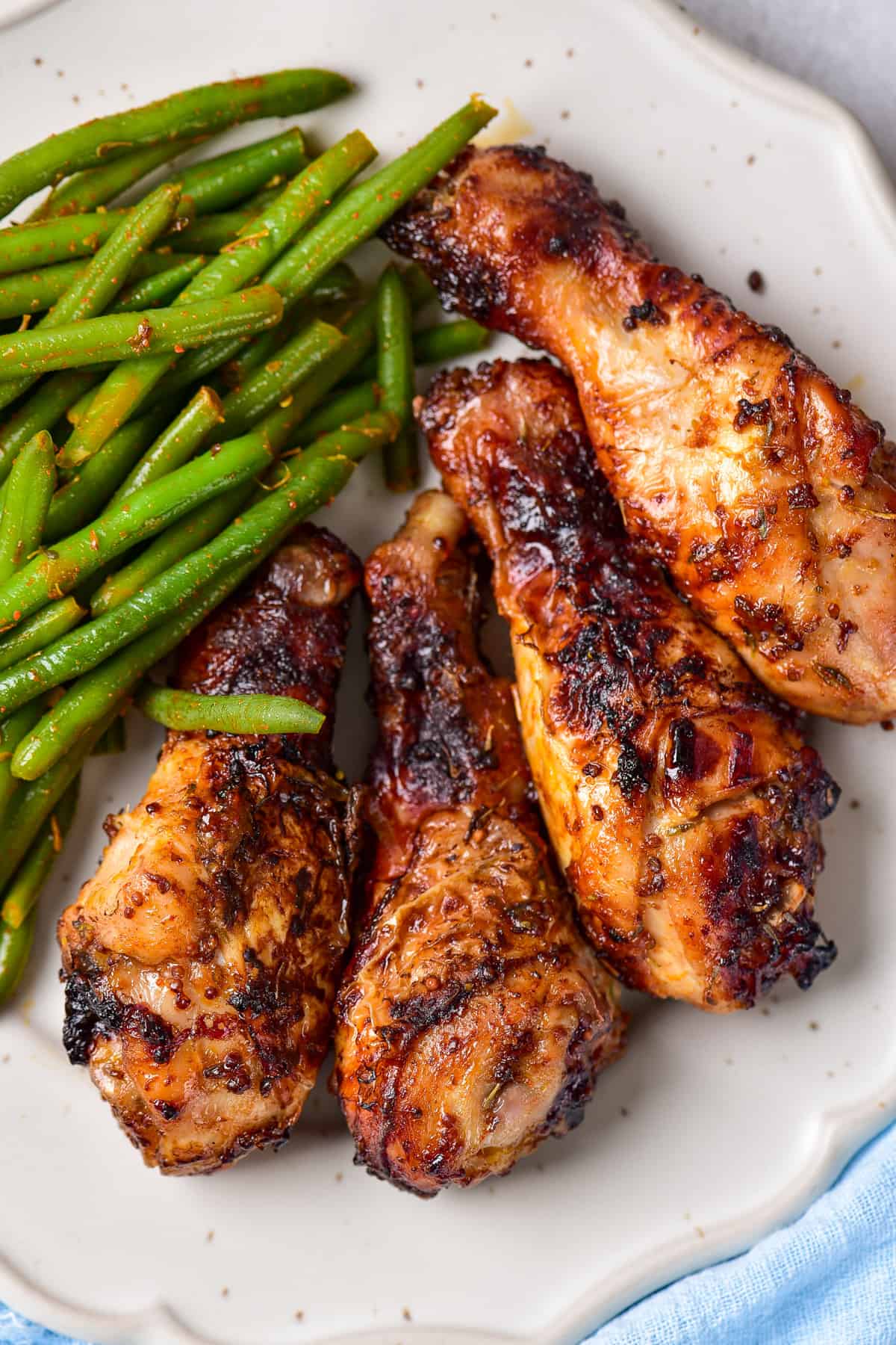 Baked chicken legs on a plate with green beans.