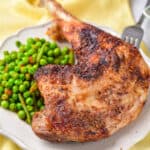 A plate with a roasted turkey leg and green vegetables.