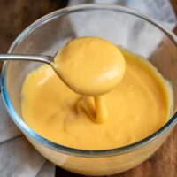 Spoon coming out of a bowl of microwave cheese sauce.