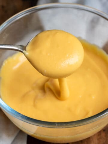 Spoon coming out of a bowl of microwave cheese sauce.