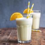 Table with two glasses of Orange Julius with straws and orange slice garnishes.