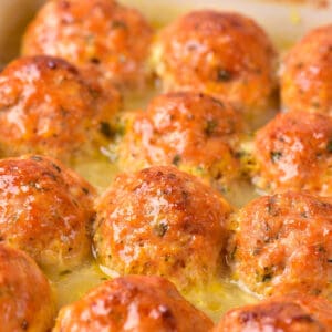 Close up of baked chicken meatballs in a baking dish.