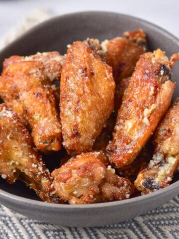 Table with a bowl of garlic parmesan wings.