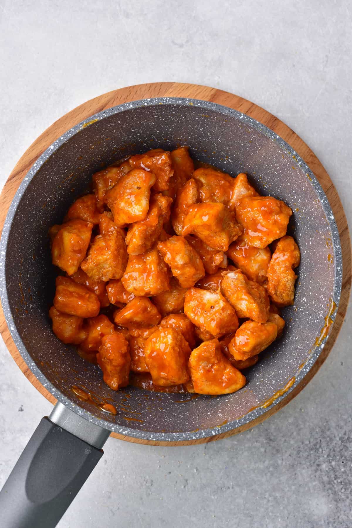 Tossing the crispy chicken bites in Buffalo sauce.