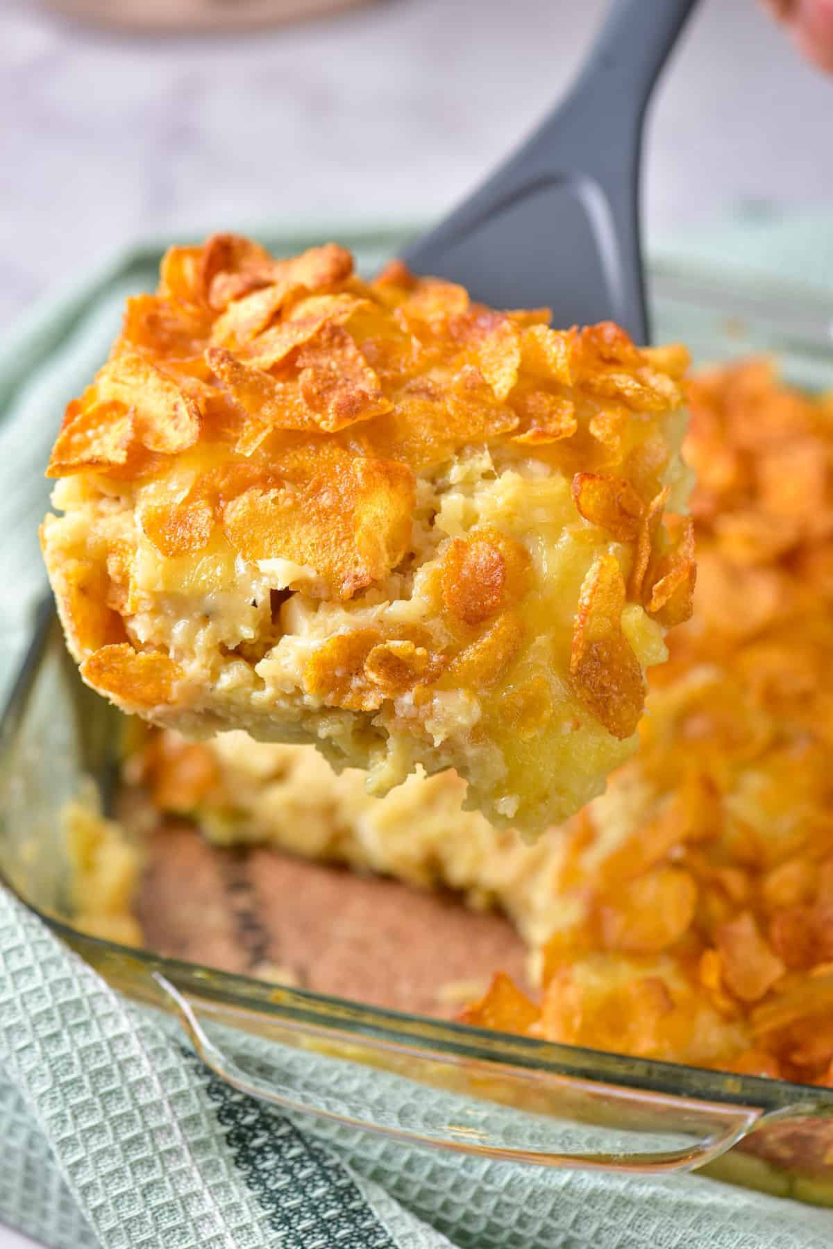 A slice of hashbrown breakfast casserole being lifted out of the baking dish.