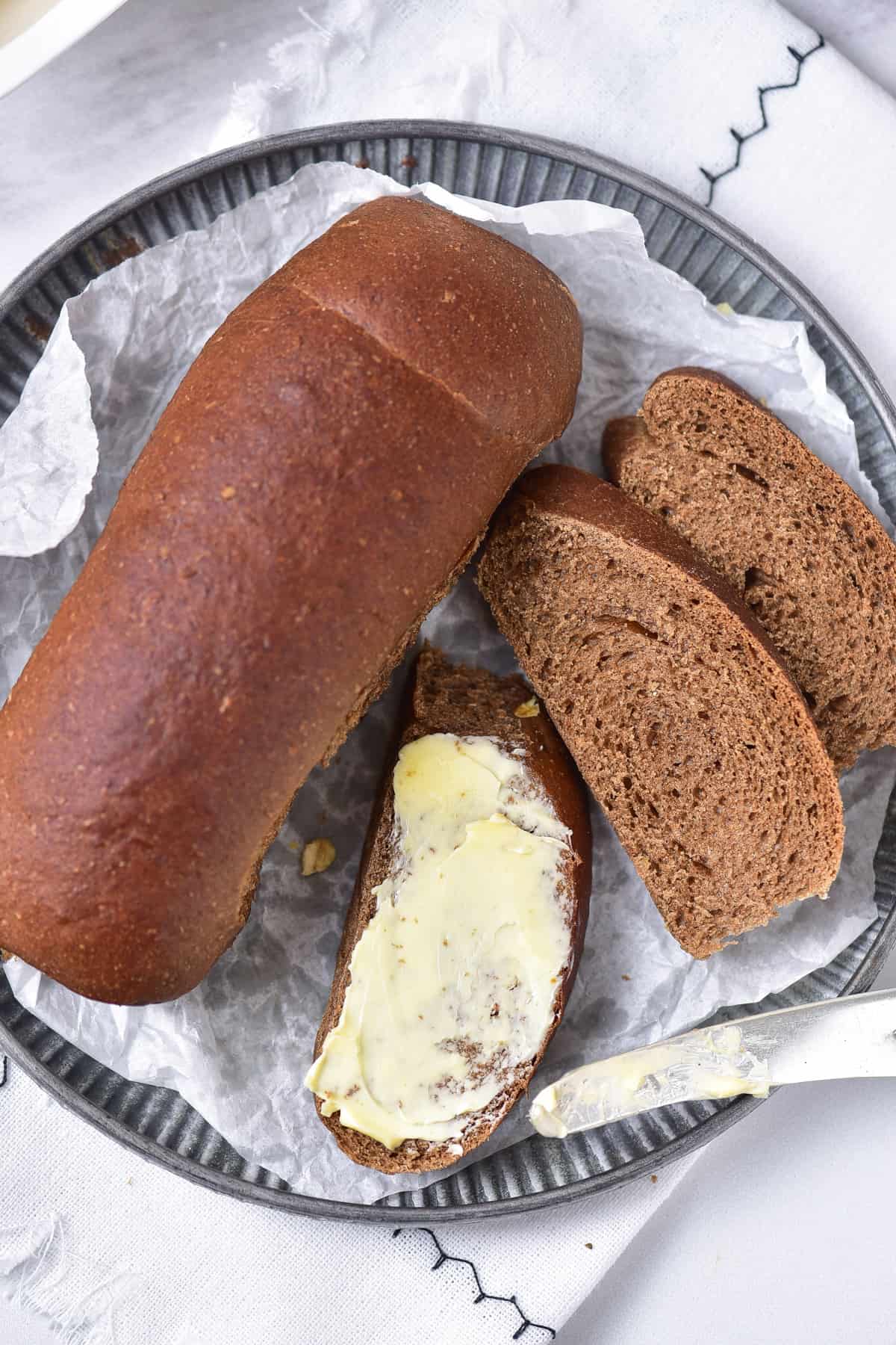 Sliced Outback Steakhouse bread on a plate, with one spread with butter.