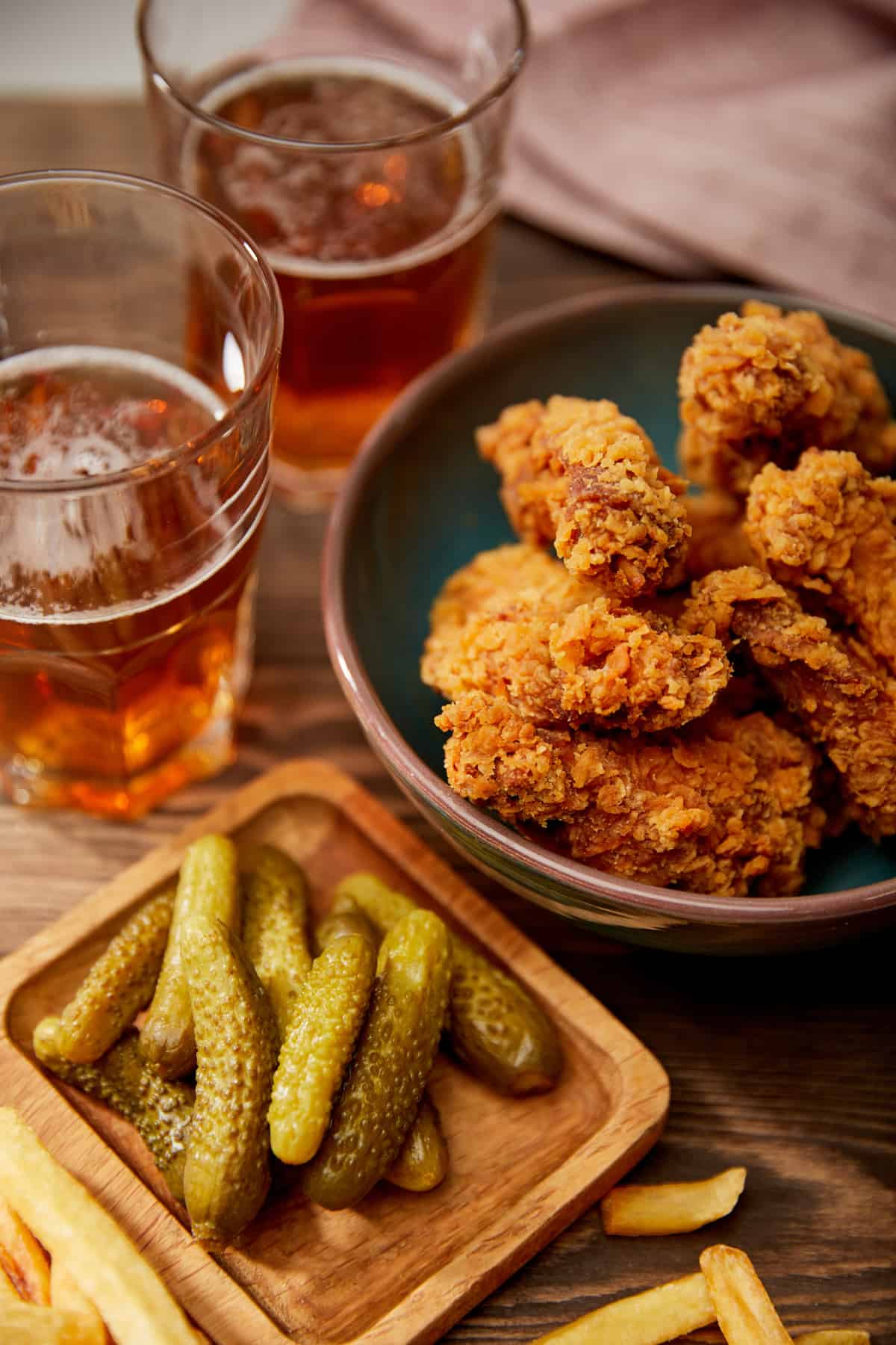 Breaded chicken tenders, pickles and beer on a table to show pub food.