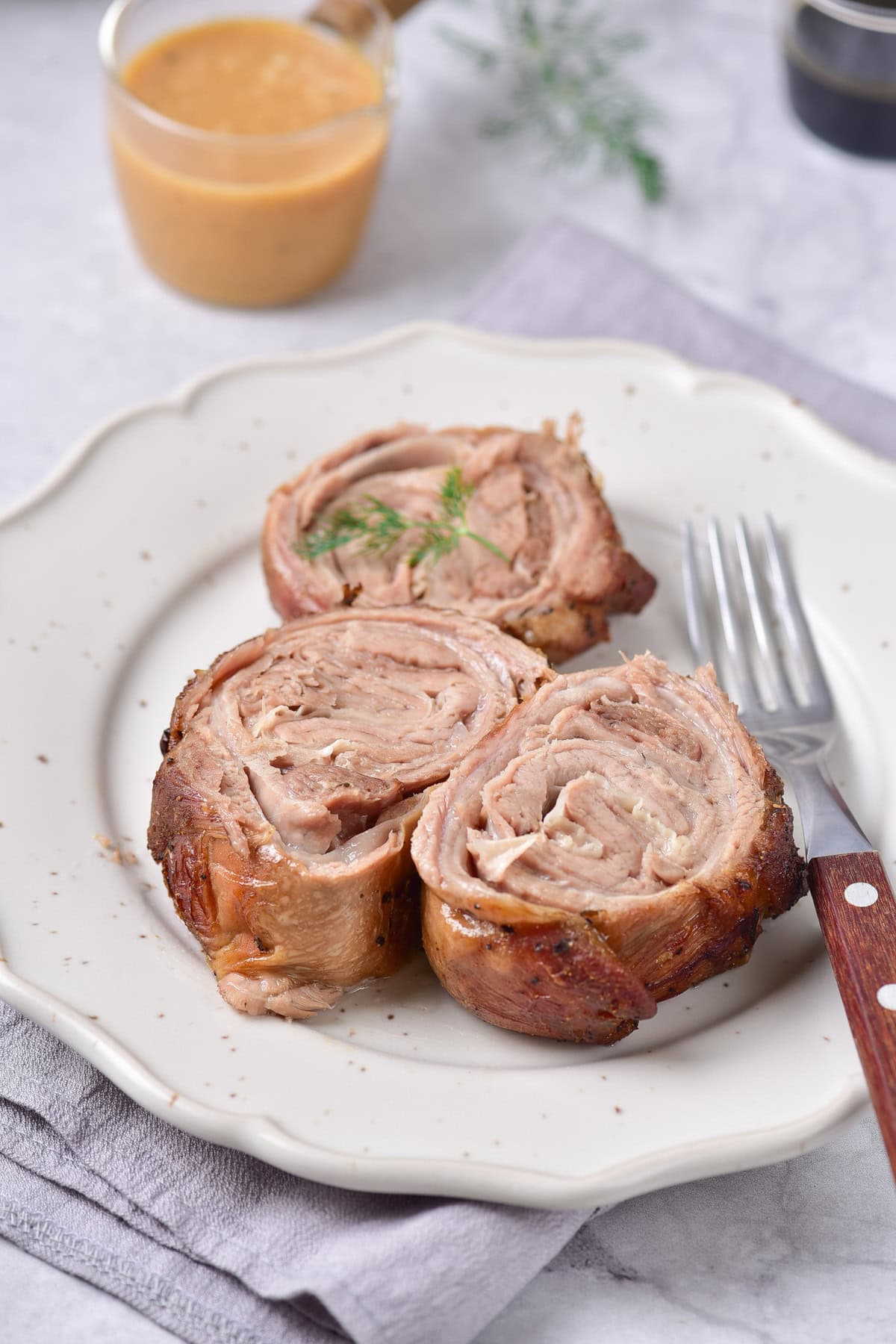 Three slices of roasted rolled lamb on a plate.
