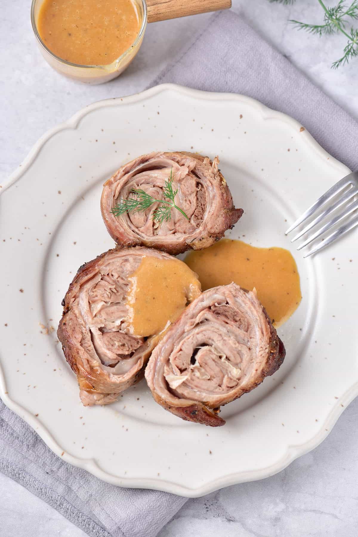 A plate of roasted rolled lamb with gravy.