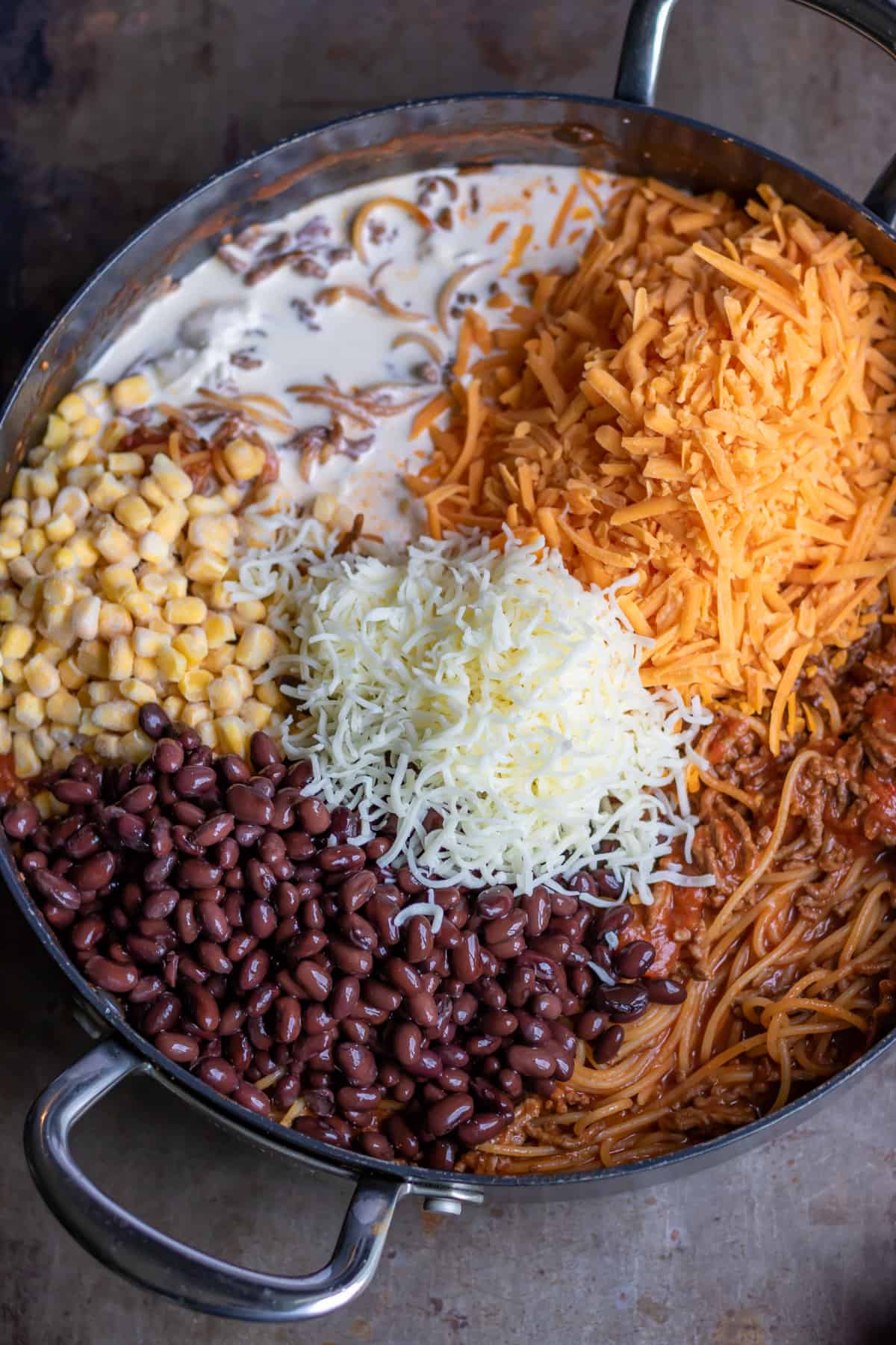 Adding the corn, beans, cream and cheeses to the pot.