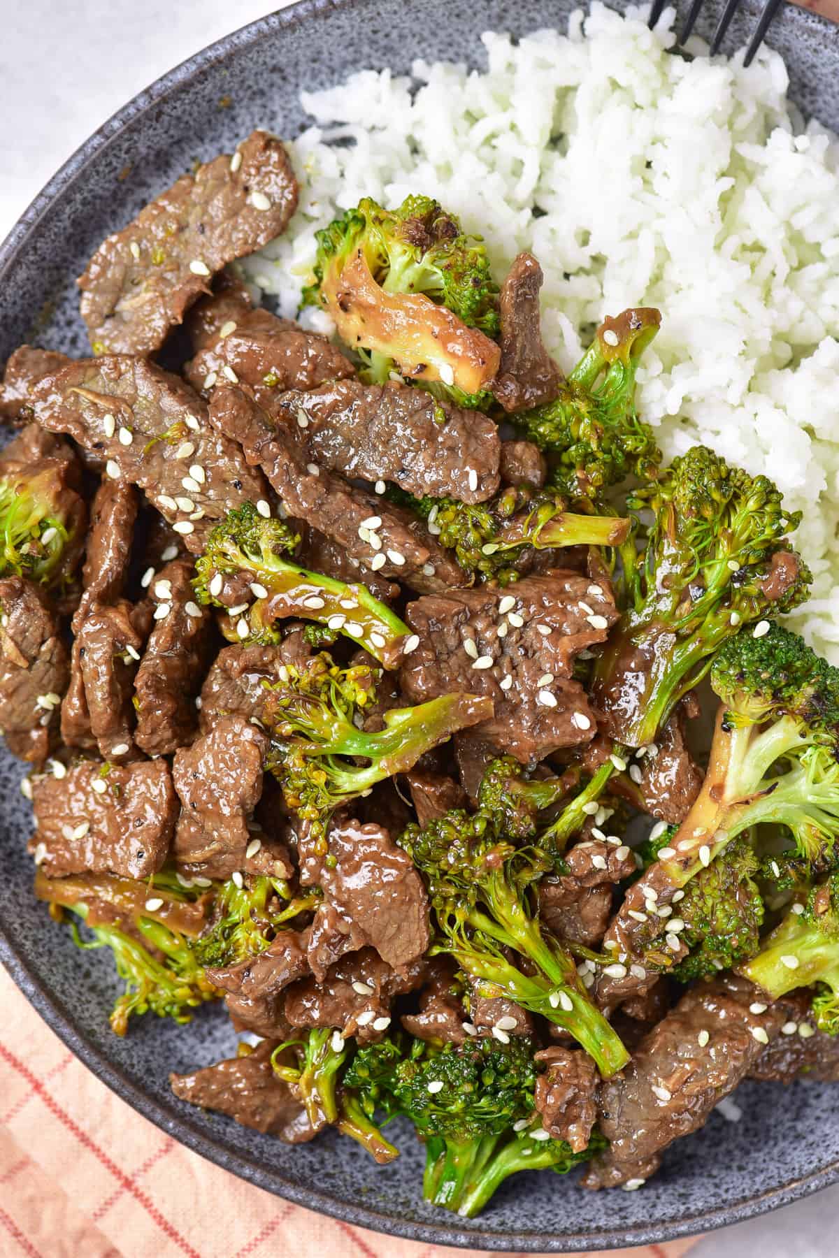 Close up looking down at a dish of beef, broccoli and rice.