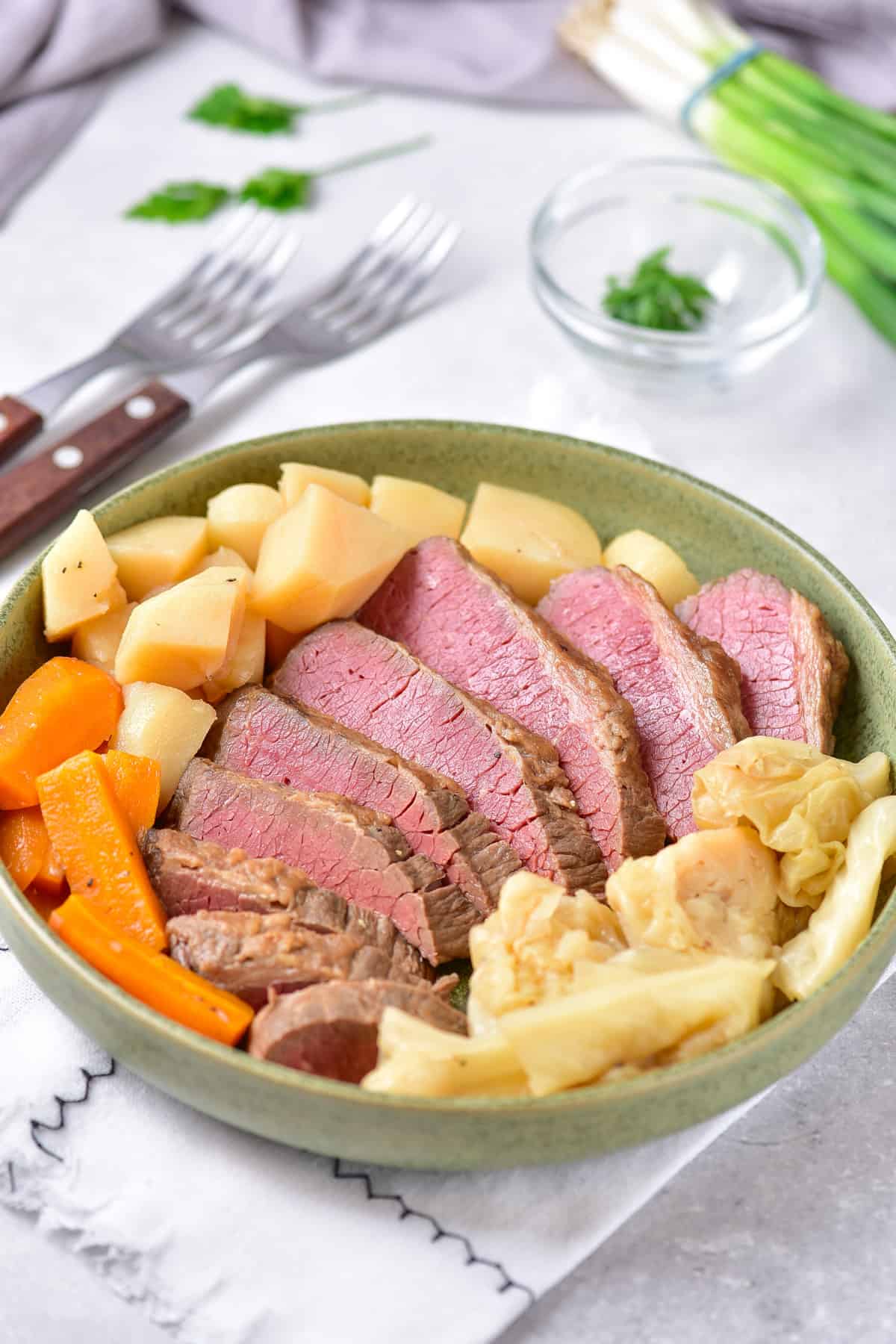 Table with a plate of corned beef with cabbage, potatoes and carrots.